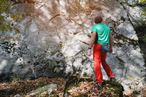 A man aged climber stands in front of a training rock in the forest. Climbing training — Stock Photo, Image