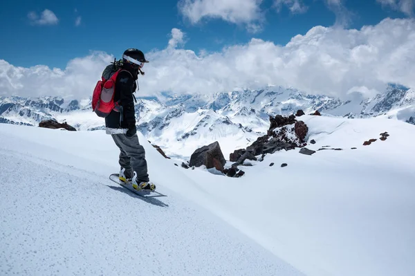 Genç kadın snowboardcu, dağların zirvesinde güneşli bir günde, yamaçta kar kayağı yapmaya hazırlanıyor. — Stok fotoğraf