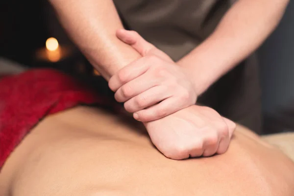 Ryggmassage. Manlig massör gör rygg massage till manlig klient i mörkt rum spa salong — Stockfoto