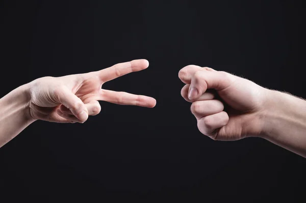Male and female hands play paper scissors stone on a black background. The concept of resolving conflicts in a peaceful and ecological way — Stock Photo, Image