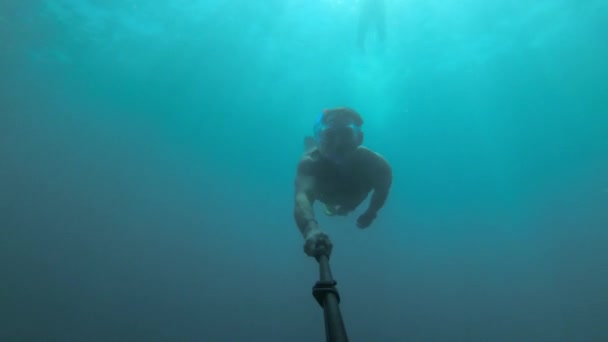 Спортивный молодой человек в маске и с трубкой с плавниками и глубокими погружениями плавает под водой. — стоковое видео