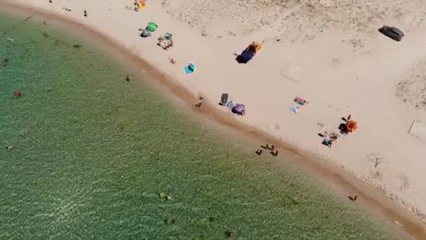 Вид с воздуха на лазурный пляж центральной Азии с отдыхающими туристами и пляжными зонтиками. Предпосылки для туризма и отдыха у моря — стоковое видео