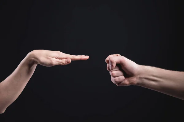 Mannelijke en vrouwelijke handen spelen papieren schaar steen op een zwarte achtergrond. Het concept van een vreedzame en ecologische oplossing van conflicten — Stockfoto