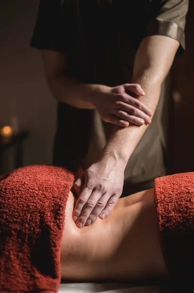 Close-up van een man doet een onderrug massage aan een vrouw klant in een donkere kamer van een spa massage salon — Stockfoto