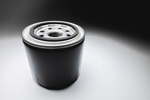 Black new oil filter in contrasting light on a black and white background. Wide angle — Stock Photo, Image