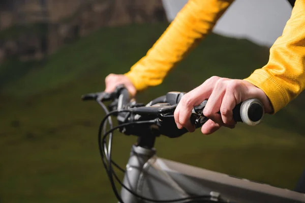 Close-up of female hands holding the handlebars of a mountain bike in the summer in the mountains — Stock Photo, Image