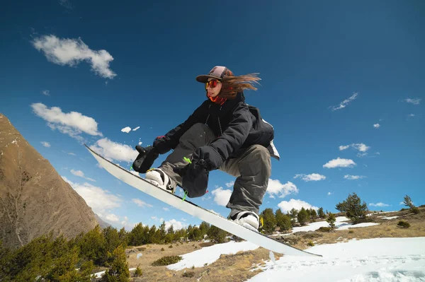 Mulher atleta snowboarder voa depois de saltar de kicker fazendo truque — Fotografia de Stock