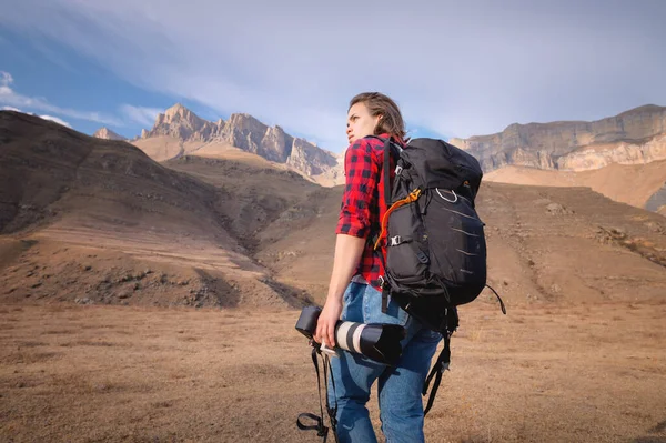 Mladá žena turista fotograf těší pohled na vrchol hory s kamerou v rukou na pozadí hor — Stock fotografie