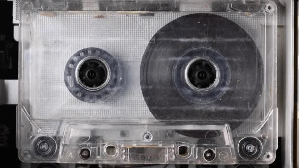 閉じるテープレコーダーはオーディオカセットを再生しています。接近中だ。ヴィンテージのオーディオカセットは、レトロなカセットプレーヤーでサウンドを録音するために使用される空白のラベルテープに回転します。会話の記録. — ストック動画