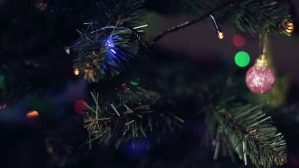 Gros plan faible profondeur de champ d'une petite main de filles avec une manucure festive accroche de beaux jouets sur un arbre de Noël artificiel — Video