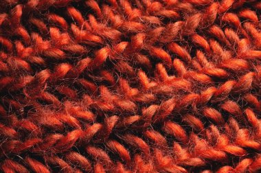 Topak topak örülmüş kırmızı bir süveterin içinde örülmüş kabloların yakın çekimi