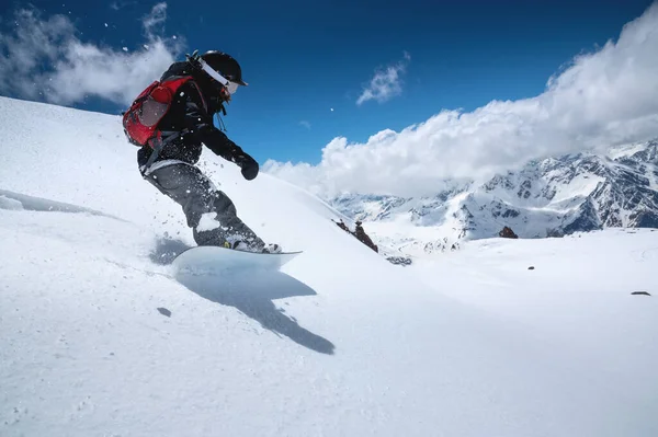 Mujer joven snowboarder en nieve profunda - freeride extremo en el fondo de las montañas cubiertas de nieve en un día soleado — Foto de Stock