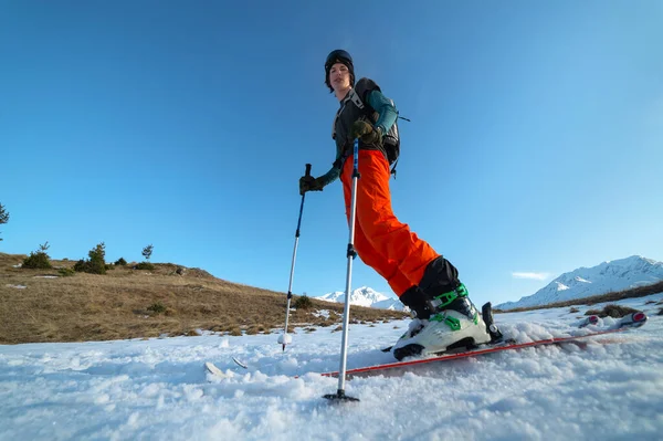 Lekker skiën in de besneeuwde bergen bij zonsondergang. Een jongeman atleet skiër staat in de bergen. Onderaanzicht brede hoek — Stockfoto