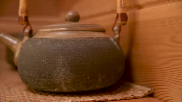 Yixing klei theepot voor een handgemaakte theeceremonie naast ander aardewerk op een houten plank in de kamer — Stockvideo