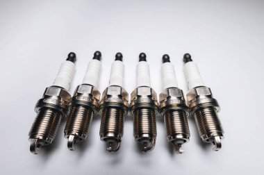 Gri arkaplanda 6 silindirli motoru olan araba için yeni buji kitleri