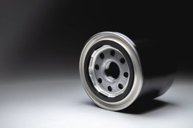 Yeni yağ filtresi, gri bir arka planda siyah bir konutta. Yeni yedek parçalar