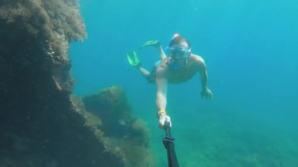 Pemuda penyelam bebas dengan topeng berenang di bawah air di samping perahu yang tenggelam. Kamera aksi tongkat selfie — Stok Video