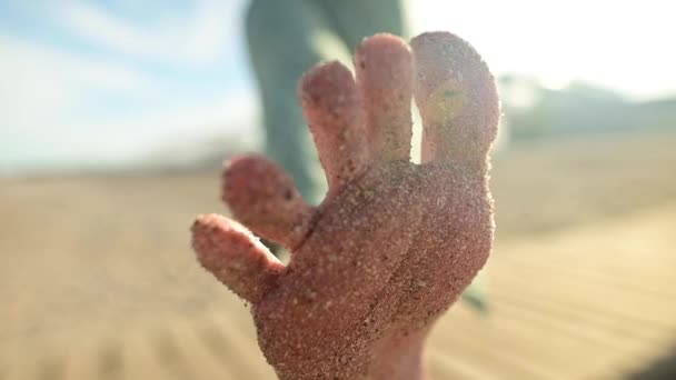 Zbliżenie stóp i stóp w piasku młodej dziewczyny w zwolnionym tempie. Kręci palcami na piaszczystej plaży w słoneczny dzień — Wideo stockowe