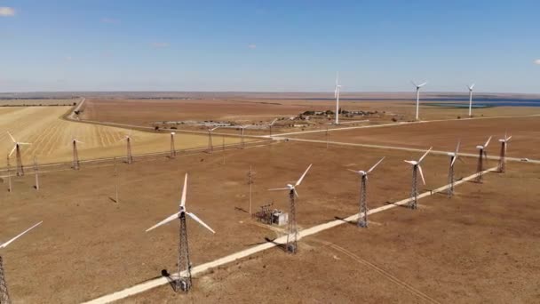 Aerial view of wind turbines generating clean wind power among yellow fields. Renewable energy production in wind-driven steppe regions. — Stock Video