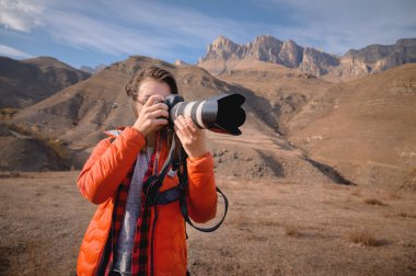 Profesyonel bir fotoğrafçı ve sırt çantalı ve elinde profesyonel bir kamera olan çekici bir kadın fotoğraf makinesiyle fotoğraf çekiyor.