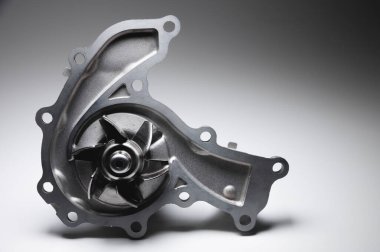 Gri arka planda yeni bir içten yanmalı motorun soğutucu su pompasının yakın çekimi. Karşıtlık ışığı