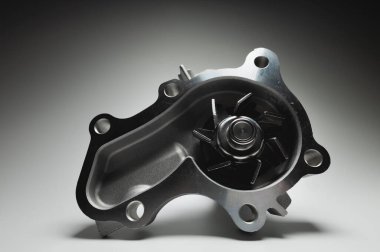 Gri arka planda yeni bir içten yanmalı motorun soğutucu su pompasının yakın çekimi. Karşıtlık ışığı