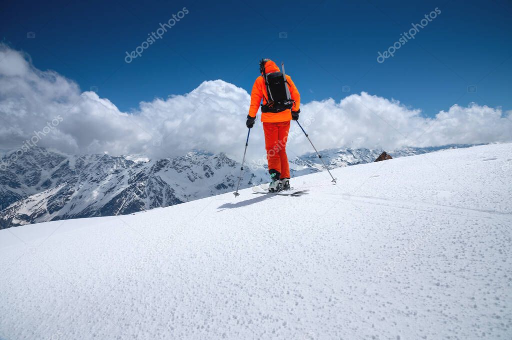 Portrait of a young male athlete skier in a ski tour on skis on the background of snow-capped mountains on a sunny day. Skitour professional
