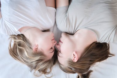 Genç, çekici heteroseksüel çift, kadın ve erkek, gündelik giysiler içinde yatak odasındaki yatağa uzanıyorlar. Hafta sonu yatakta dinlenmek iyi bir zamandır.