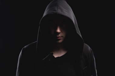 Kapüşonlu bir adamın stüdyo portresi, bir gölge yüzünü gizliyor. Anonimlik gölge ekonomi ve kanundan kaçma