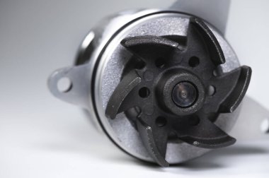 Gri arka planda yeni bir içten yanmalı motorun soğutucu su pompasının yakın çekimi. Karşıtlık ışığı