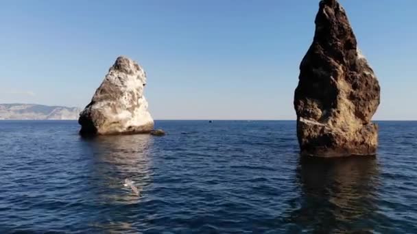 Tek tek kayaların ve yüksek kayalıkların yanındaki teknelerin deniz kıyısındaki hava manzarası. Lüks Akdeniz tatilleri — Stok video