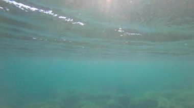 Dalgaların yüzeyinin yansımasında suyun altından deniz arka planının soyut görüntüsü ve güneş ışınları parlıyor ve parlıyor.