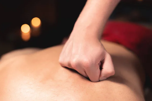 Close-up Jonge Kaukasische mannelijke massagesit maakt een professionele massage aan een atleet om een patiënt in een donkere kamer herstel massage kamer — Stockfoto