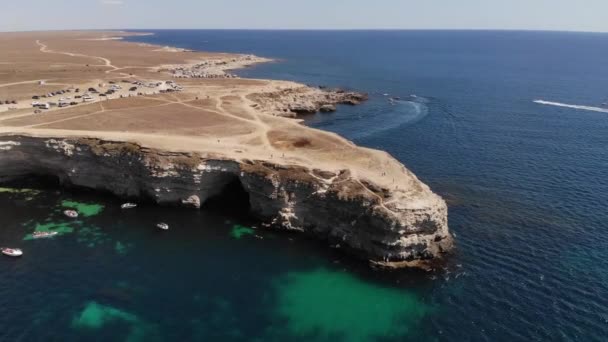 Vue du dessus d'en haut. Images aériennes du drone 4K. Mer cristalline océan avec bateaux de tourisme et petits navires. Cap avec de hautes falaises — Video