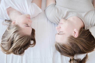 Yakın plan. Genç, çekici heteroseksüel çift ve kadın. Yatak odasındaki yatağa uzanmış gündelik giysiler giymişler..