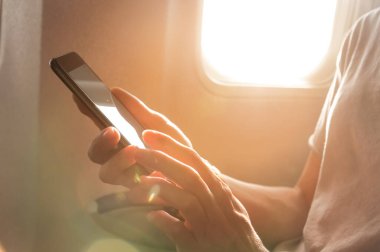 Kadınların elleri boş masaüstü ekranlı siyah akıllı bir telefon tutuyor. Pencere uçağının yanındaki kulübede.