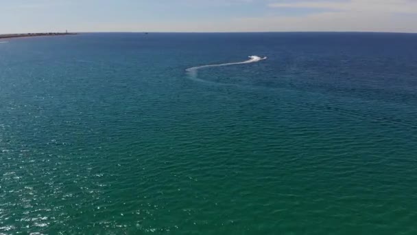 Vista aérea de tubos remolcados inflables para rodar a los turistas en un tubo atado a la moto acuática a través del mar azul en un día soleado — Vídeo de stock