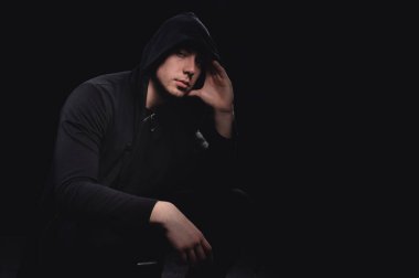 Kapüşonlu bir adamın stüdyo portresi, bir gölge yüzünü gizliyor. Anonimlik gölge ekonomi ve kanundan kaçma