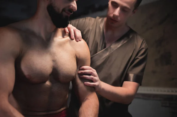 Primo piano Massaggio sportivo professionale alle spalle. Atleta di sesso maschile che riceve massaggio da massaggiatore maschile — Foto Stock