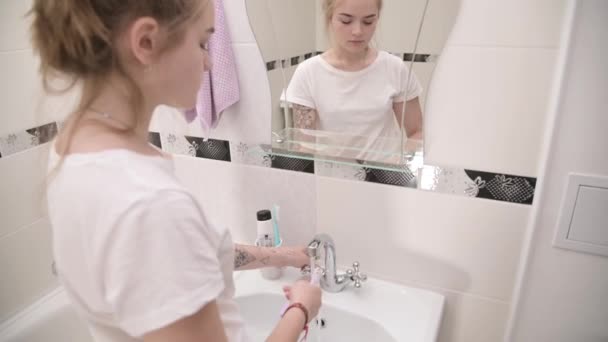 Jeune femme devant un miroir dans la salle de bain applique du dentifrice sur une brosse à dents — Video