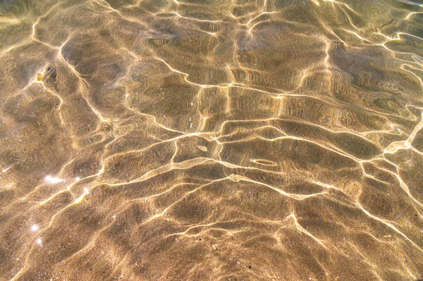 Közeli, nyugodt, átlátszó vízfelület, homokos fenék, vakító fény, napos nap — Stock Fotó