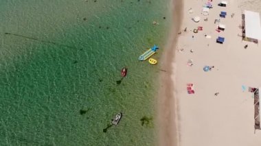 Orta Asya 'nın gökyüzü manzarası, dinlenen turistler ve plaj şemsiyeleri. Deniz kenarında turizm ve eğlence için arka plan