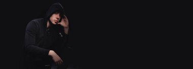 Kapüşonlu bir adamın stüdyo portresi, bir gölge yüzünü gizliyor. Anonimlik gölge ekonomi ve kanundan kaçma