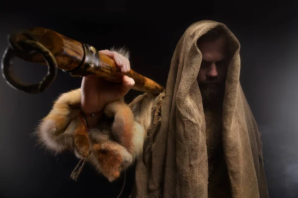 Portrait of a medieval bearded military monk, dressed in animal skins and burlap, holding a battle ax. Low key. Focus on your clothes. Atmospheric portrait of a character from a RPG game — Stock Photo, Image
