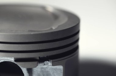 Gri arkaplandaki içten yanmalı motorun yakın çekim pistonu. Motor tamiri için yeni yedek parçalar.