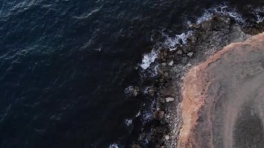 Uçuşun dik kayalık kıyı şeridi üzerindeki havadan görüntüsü. Dalgalar ve köpüklerle dolu bir fırtına sırasında deniz.