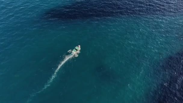Vista aérea de um barco a motor que navega através do mar azul-turquesa claro em um dia ensolarado. Turismo marítimo e passeios de barco pelo mar — Vídeo de Stock