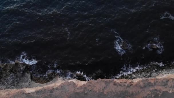 Luchtfoto van de vlucht over steile rotsachtige kustlijn. De zee tijdens een storm met golven en schuim — Stockvideo