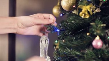 Yakın plan beyaz kadın eli beyaz beyaz tarlanın derinliği Noel ağacına parlak oyuncaklar asar. Yüzen odaklı yeni yıl havası