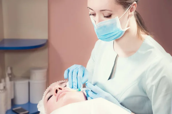 Kosmetologie. Nahaufnahme der Hand der Kosmetikerin und des Gesichts der Patientin vor der Injektion von Hylauronsäure oder Botox — Stockfoto